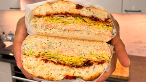 Chef James Cochran holding a salmon sandwich to the camera