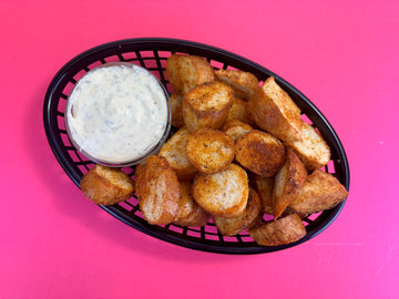 A pink background with black bowl filled with BBQ Bagel bites on top, next to a large part of Sauce Shop Ranch Mayo