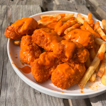 buffalo scampi and fries with buffalo hot sauce poured over them