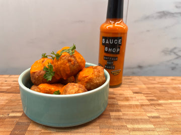 a bowl of potato pops covered in Buffalo Hot Sauce with a Buffalo Hot Sauce bottle in the background