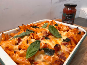 A spicy pasta bake in an oven dish, with Sauce Shop Spicy Marinara Simmer-Sauce in the background