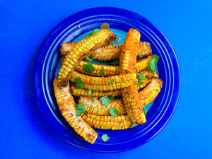 A plate of buffalo corn ribs with a blue background
